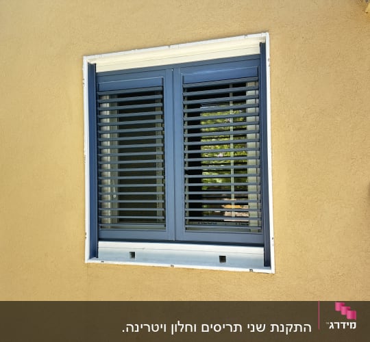 חלון עם תריסים כחולים על קיר צהוב